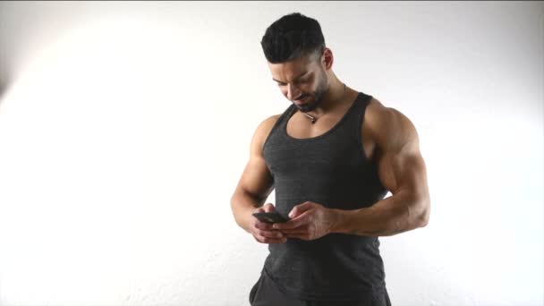 Muskularny mężczyzna przy użyciu telefonu komórkowego — Wideo stockowe