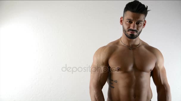 Muscular culturista por pared blanca — Vídeo de stock