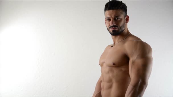 Bodybuilder musculaire par mur blanc — Video