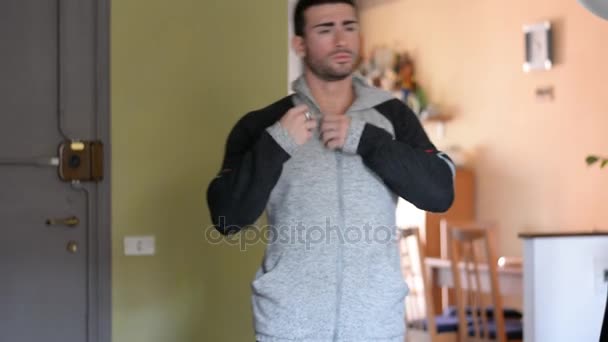 Мускулистый мужчина открывает свитер на обнаженном мышечном туловище — стоковое видео