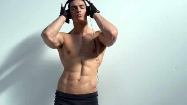 Muscular culturista escuchando música con auriculares — Vídeos de Stock