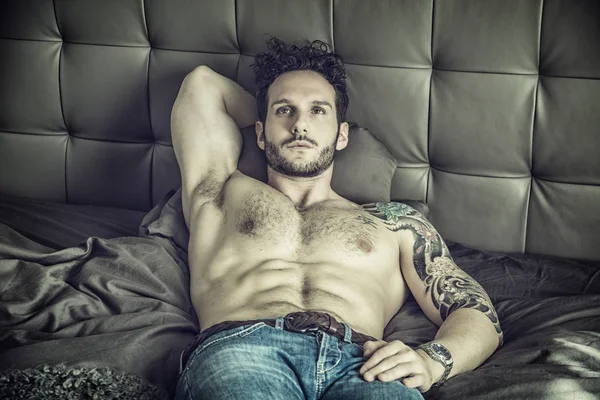 Paidaton seksikäs mies malli makaa yksin sängyllään — kuvapankkivalokuva