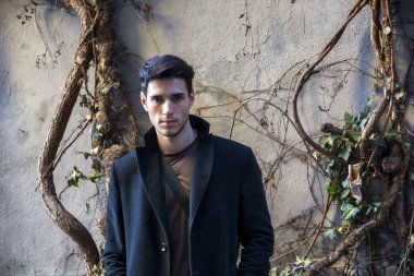 Ağaca yaslanan yakışıklı genç adam.