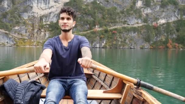 Hombre joven remando en barco en el lago de montaña — Vídeo de stock