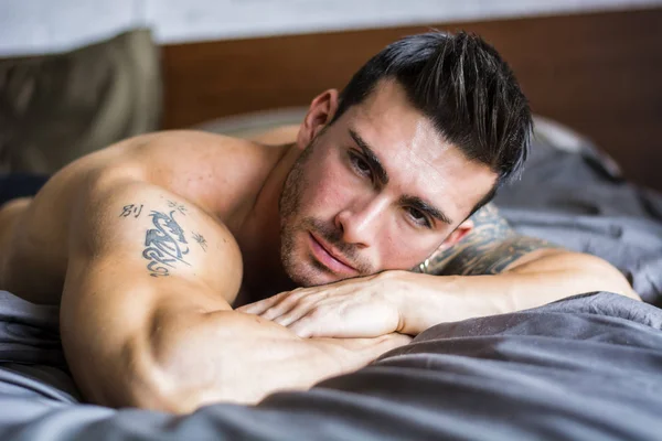 Shirtless sexy modelo masculino tumbado solo en su cama Imágenes de stock libres de derechos