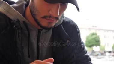 Cep telefonu oturma kullanarak Kış moda trendy yakışıklı genç adam