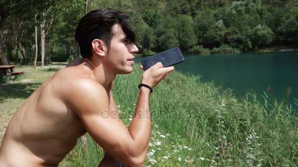 Mann verschickt Sprachnachricht mit Smartphone am See — Stockvideo