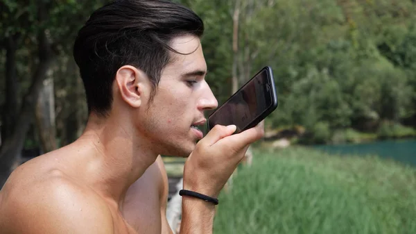 Man sending voice message with smartphone at lake — Stock Photo, Image