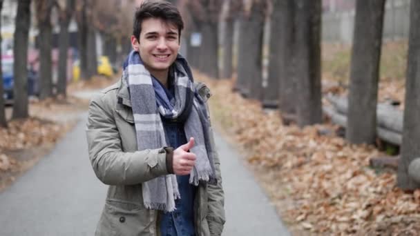 Hombre joven guapo mirando a la cámara, al aire libre — Vídeos de Stock