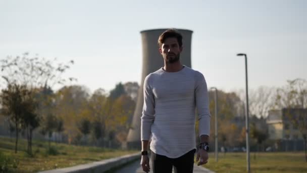 Young man in white sweater walking in city park — Stock Video