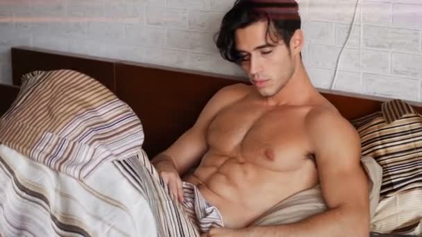 Shirtless sexy male model lying alone on his bed — Stock Video