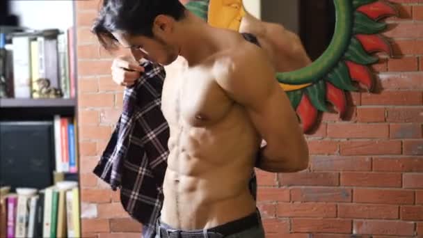 Young fit man putting on shirt on naked muscular torso — Stock Video