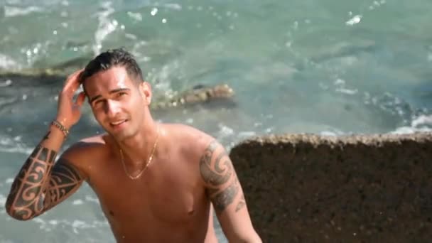 Молодий чоловік стоїть у воді на березі моря або океану , — стокове відео