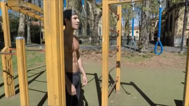 Hombre joven haciendo ejercicio en el gimnasio al aire libre — Vídeos de Stock