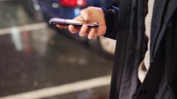 Мужские руки печатают на смартфоне под дождем — стоковое видео