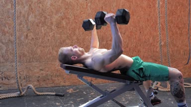 Kaslı, genç bir adam, spor salonunda göğüs kasları çalışıyor.