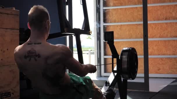 Musculoso joven, entrenando de nuevo en la máquina de remo — Vídeo de stock