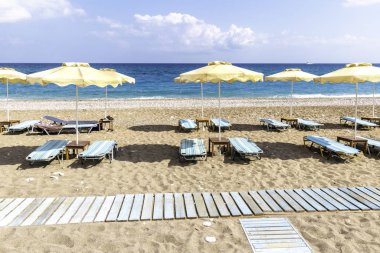 Faliraki yakınlarındaki Afandou sahilinde boş güneşlik ve şemsiye (Rhode