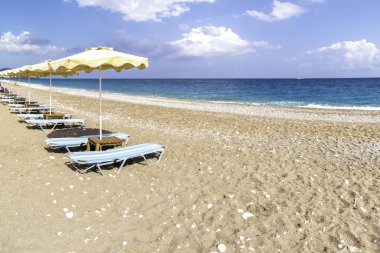 Faliraki yakınlarındaki Afandou sahilinde boş güneşlik ve şemsiye (Rhode