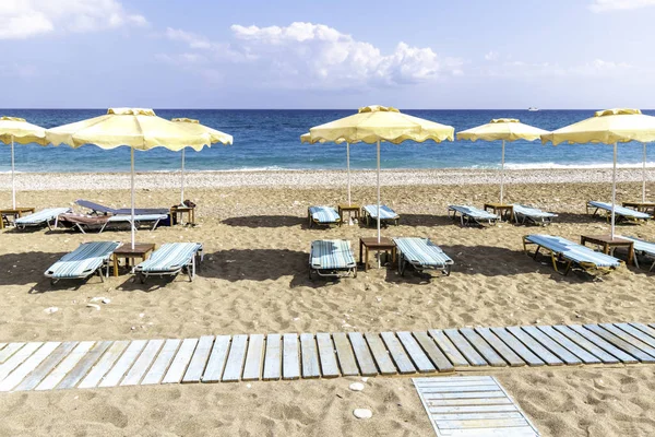 Faliraki yakınlarındaki Afandou sahilinde boş güneşlik ve şemsiye (Rhode