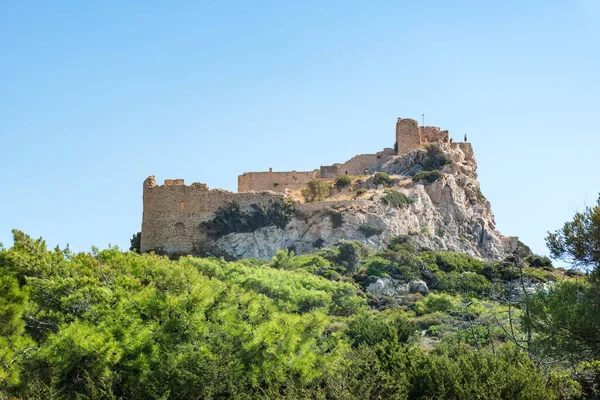 Ruins of medieval castle Kritinia on hill, green branches  (Rhodes, Greece) — Stock Photo, Image