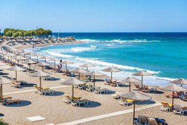 Kamiros yakınlarında insanlar, şemsiyeler ve güneşliklerle plaj (Rodos, Yunanistan)