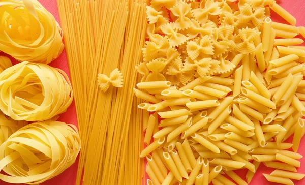 Pembe bir arka plan üzerinde yemek pişirmek için farklı makarna