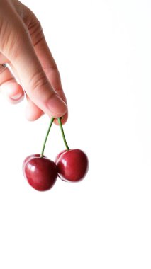 Beyaz arka plan üzerinde elinde iki kırmızı kiraz