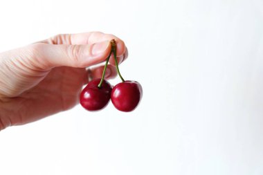  Beyaz arka plan üzerinde elinde iki kırmızı kiraz 