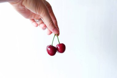  Beyaz arka plan üzerinde elinde iki kırmızı kiraz 