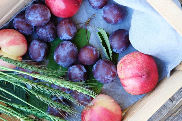 Fresh plums and peaches in a wooden box