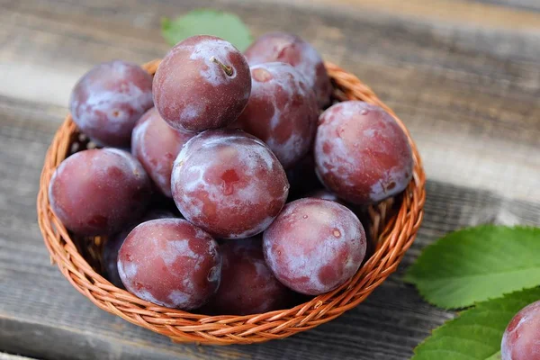 Läckra färska plommon i trä korg — Stockfoto