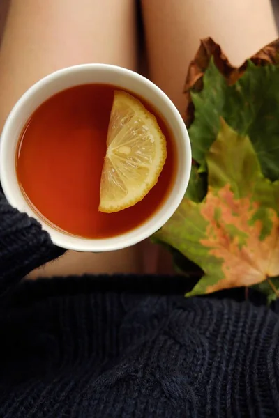 Чашка чая с лимоном в руках девушки — стоковое фото