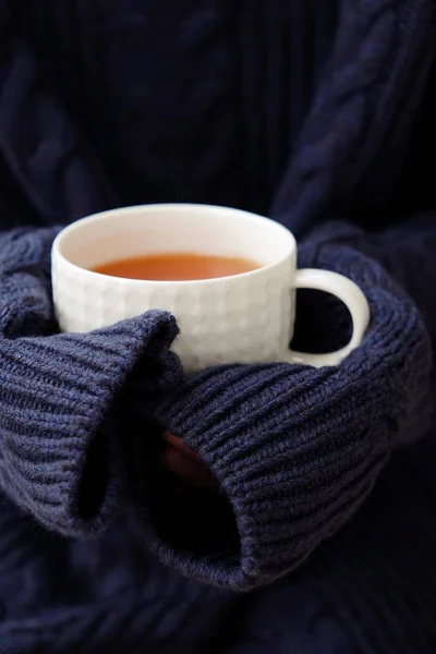 Чашка чая с лимоном в руке и свитерами — стоковое фото