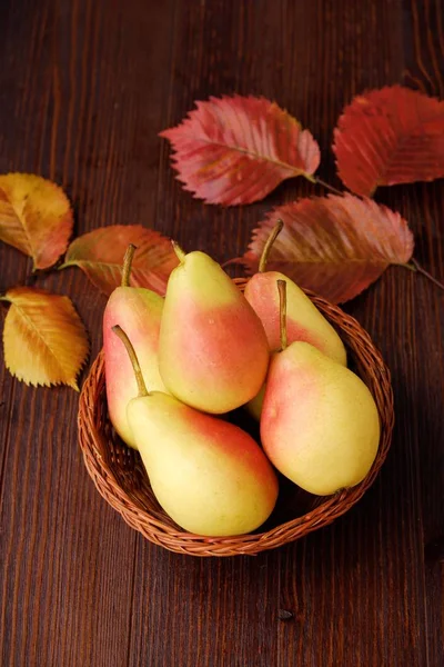 Juicy ripe yellow pears and autumn leaves in a wooden table — Stock Photo, Image