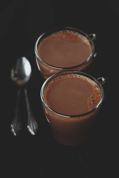 Вкусный горячий какао и ложки на деревянном фоне — стоковое фото