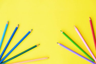Sarı arka plan görüntüsü üzerinde güzel renkli kalemler  