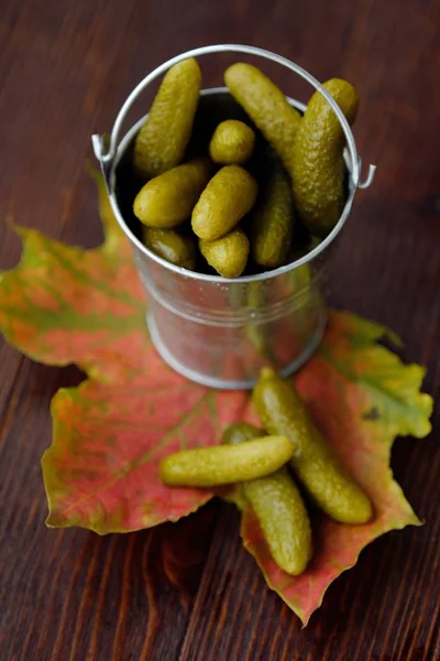 Deliciosos pepinos em conserva em um balde na mesa — Fotografia de Stock