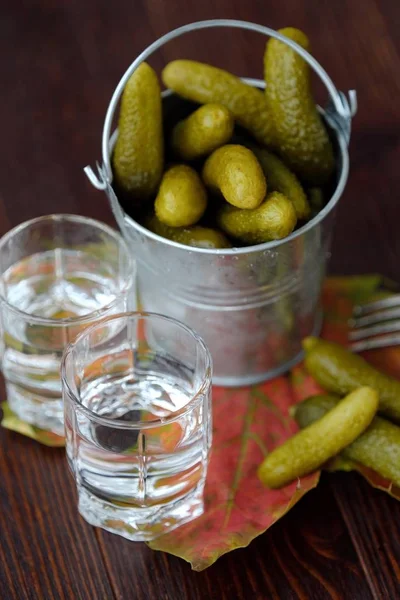 Deliciosos pepinos em conserva e vodka na mesa — Fotografia de Stock