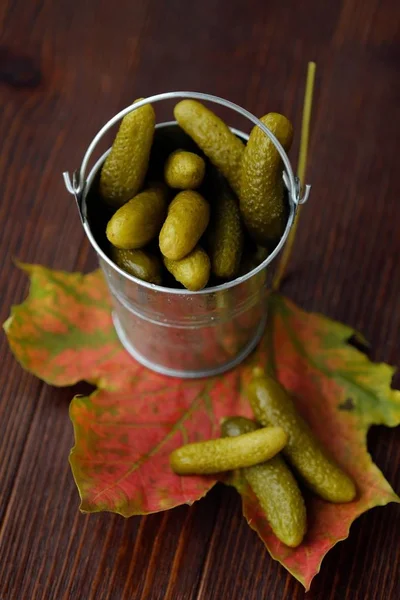Deliciosos pepinos em conserva em um balde na mesa — Fotografia de Stock