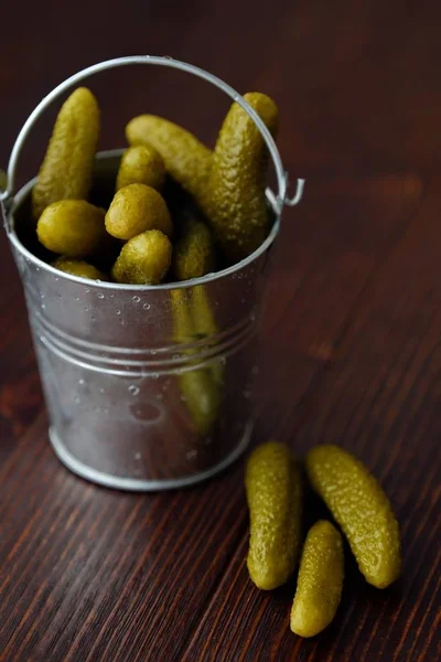 Deliciosos pepinos em conserva em um balde na mesa — Fotografia de Stock