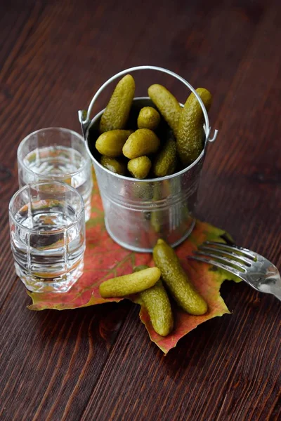 Deliciosos pepinos em conserva e vodka na mesa — Fotografia de Stock