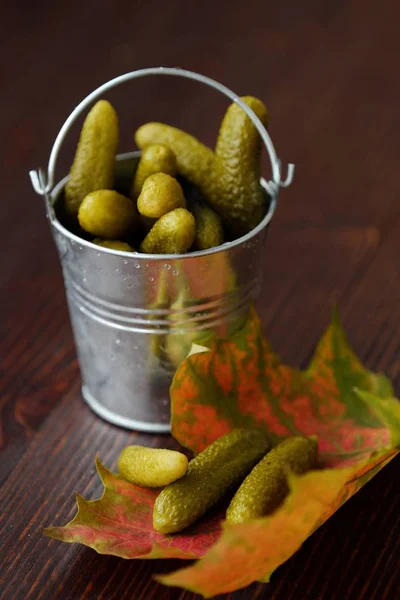 Deliciosos pepinos em conserva em um balde na mesa — Fotografia de Stock