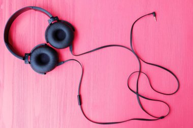 Pembe bir arka plan üzerinde büyük siyah kulaklık 
