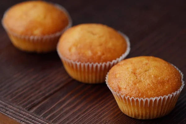 Deliciosos cupcakes frescos com creme em uma mesa de madeira — Fotografia de Stock