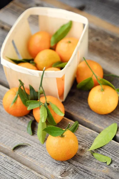 Frische leckere Mandarinen mit Blättern auf Holztisch — Stockfoto