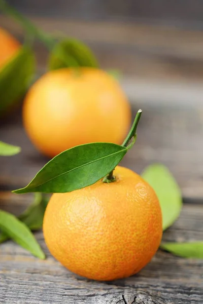 Verse, smakelijke mandarijnen met bladeren op houten tafel — Stockfoto