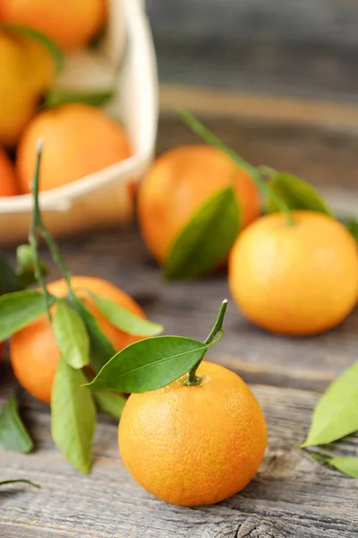 Čerstvé chutné mandarinky s listy na dřevěný stůl — Stock fotografie