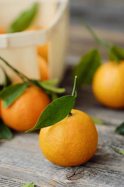 Verse, smakelijke mandarijnen met bladeren op houten tafel — Stockfoto