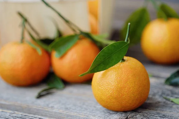 Verse, smakelijke mandarijnen met bladeren op houten tafel — Stockfoto